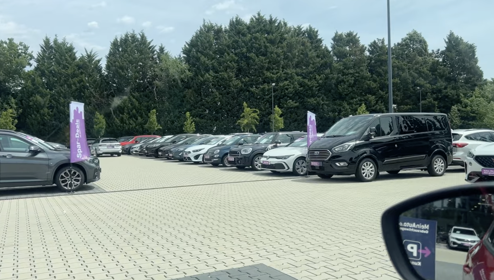 Clean, organized German used car dealership lot with rows of cars